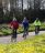 3 People riding bikes on a path through a green area.